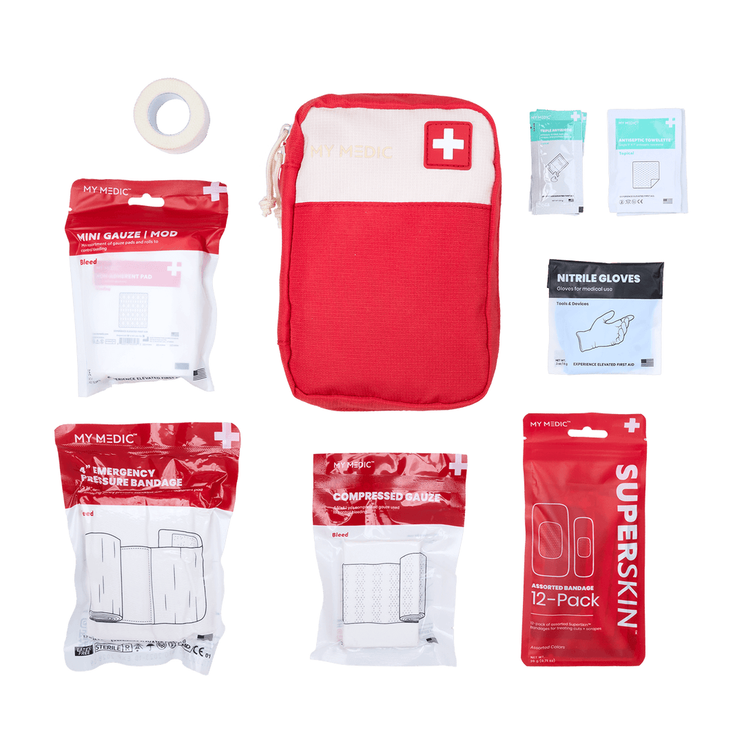 A red and white Bleeding Control first aid kit set from MY MEDIC. The kit includes a mini gauze mod, nitrile gloves, compressed gauze, emergency pressure bandage, a 12-pack of SuperSkin bandages, cloth surgical tape, tripe antibiotic ointment, and antiseptic towelettes.