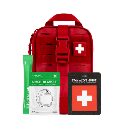 Red emergency preparedness first aid kit with a white cross patch, shown with included items: light stick, Space Blanket, and a black Stay Alive Guide booklet.